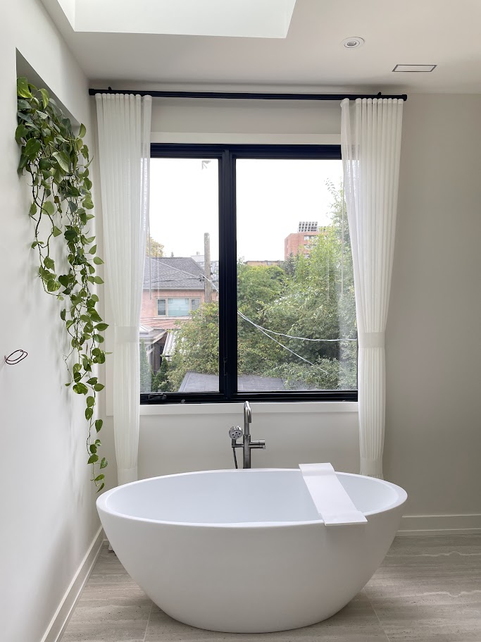 Modern bathroom with freestanding tub and white curtains