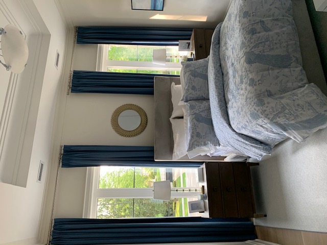 Bedroom with navy blue pinch pleat curtains and toile bedding
