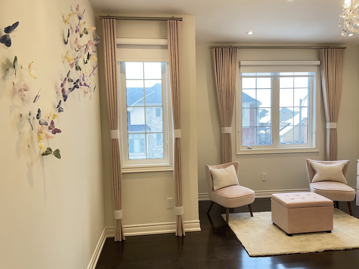 Nursery sitting area with pink curtains and butterfly wall art