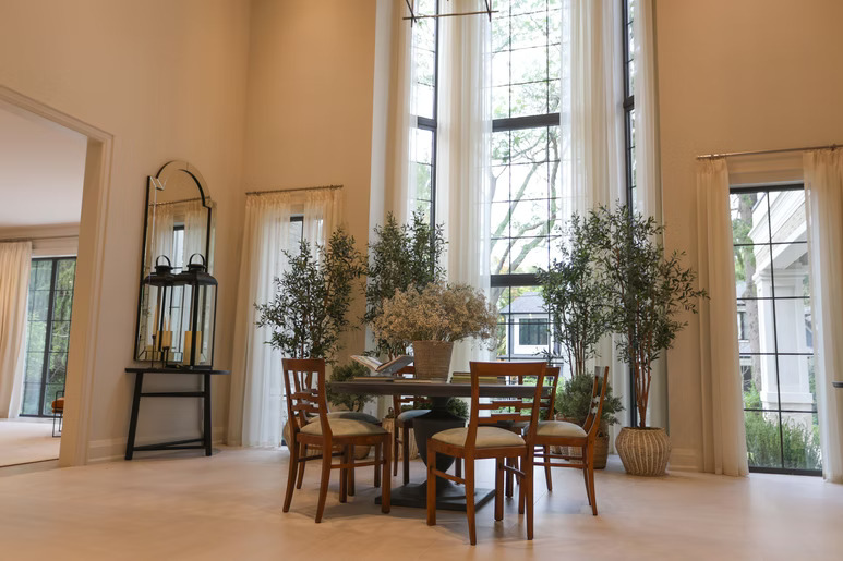 Two-story dining space with dramatic floor-to-ceiling cream drapery