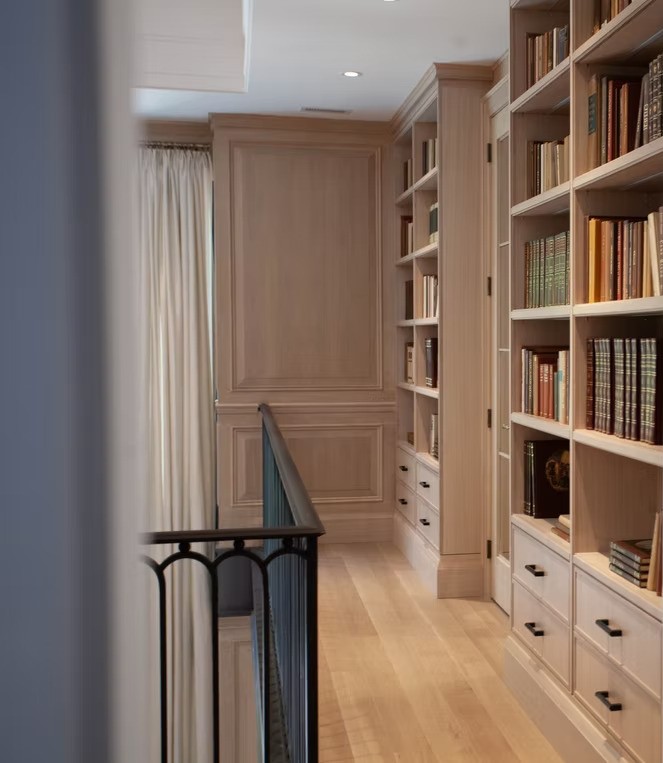 Upper landing with built-in bookshelves and neutral drapery