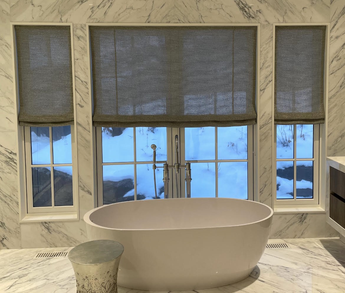 Roman shades in marble bathroom with freestanding tub